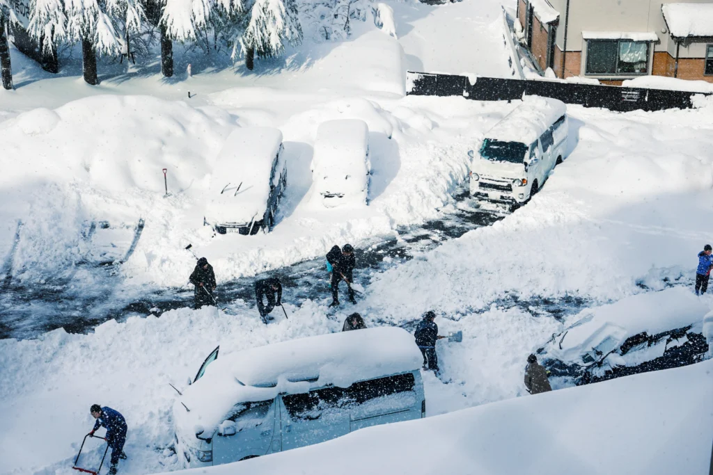 旅客在城崎溫泉飯店停車場挖掘被大雪掩埋的汽車。