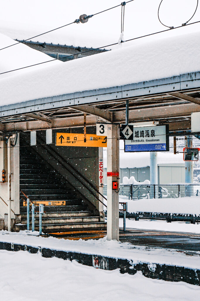 冬日大雪中緩緩駛進城崎溫泉站的特急列車,月台與軌道鋪滿白雪。