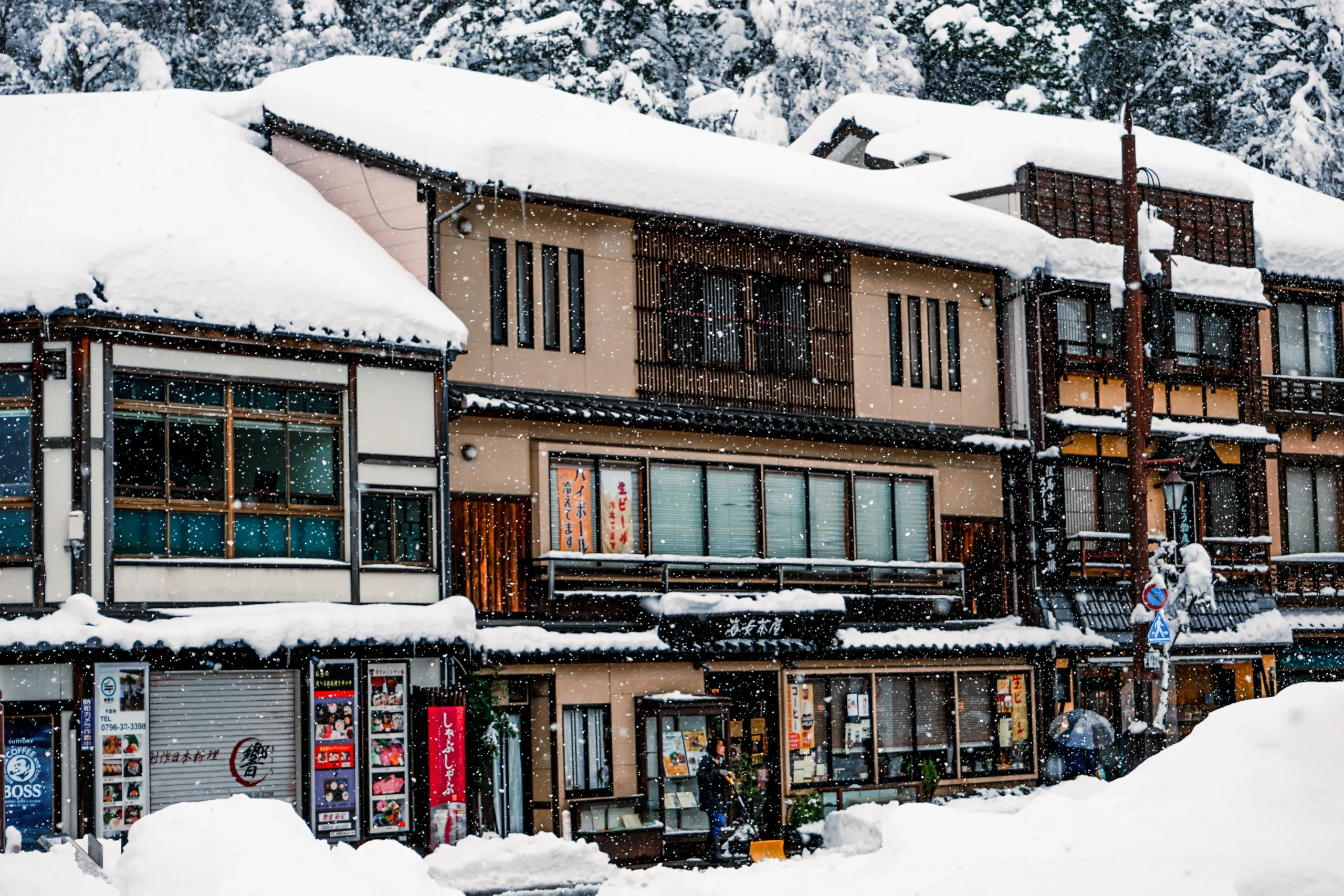 大雪紛飛的城崎溫泉街道,兩旁是傳統日式溫泉旅館。