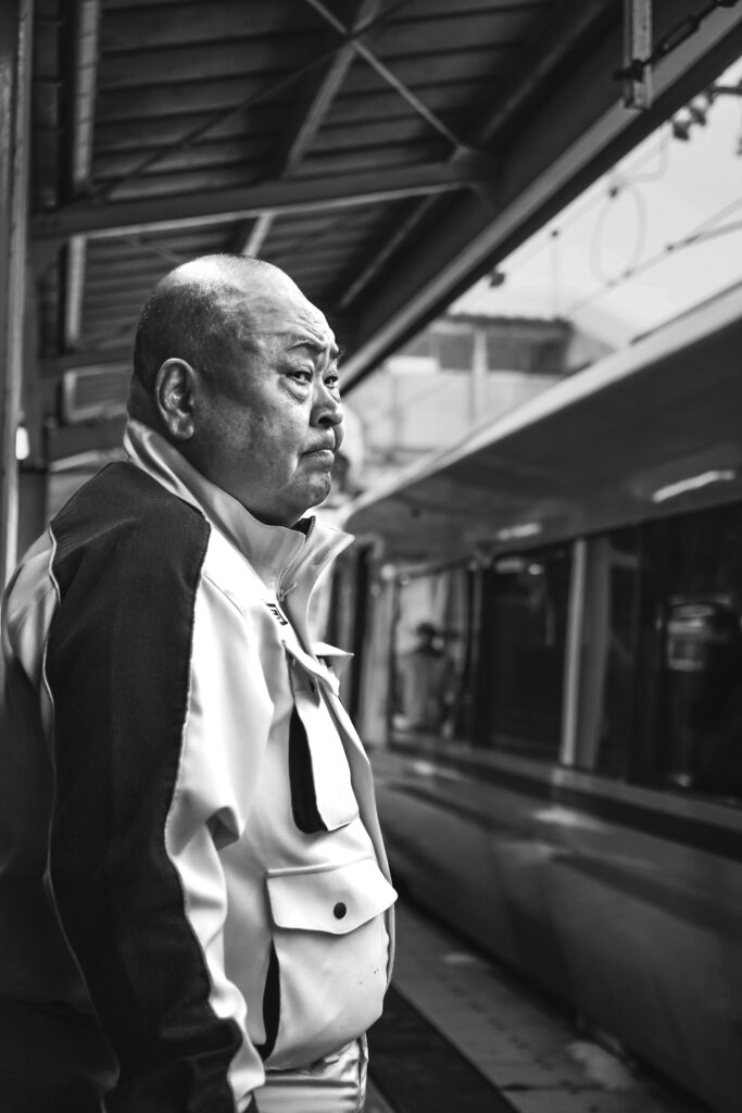 城崎溫泉車站月台上穿著紅色制服的除雪人員特寫,展現雪國職人精神。