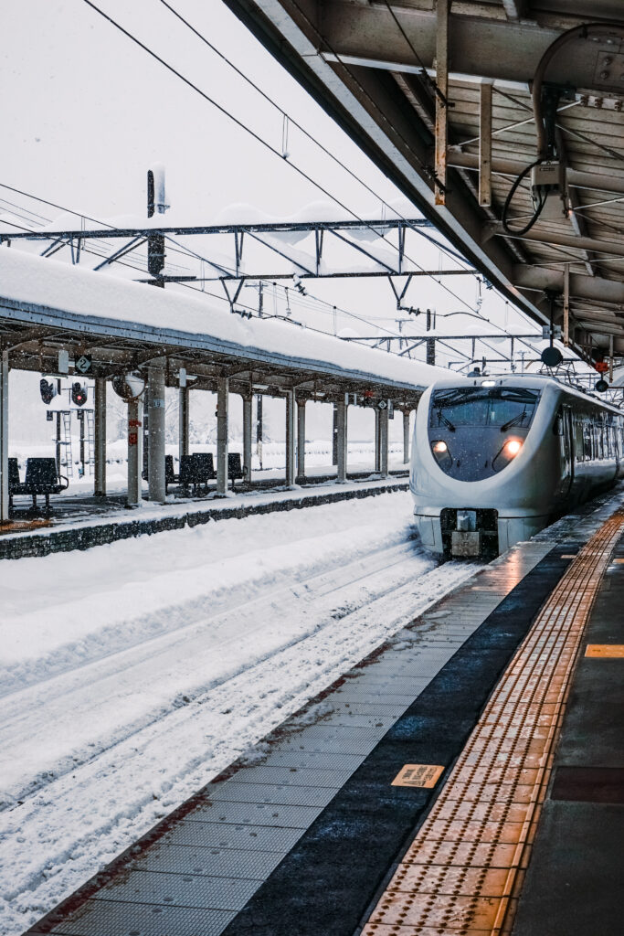 冬日大雪中緩緩駛進城崎溫泉站的特急列車,月台與軌道鋪滿白雪。